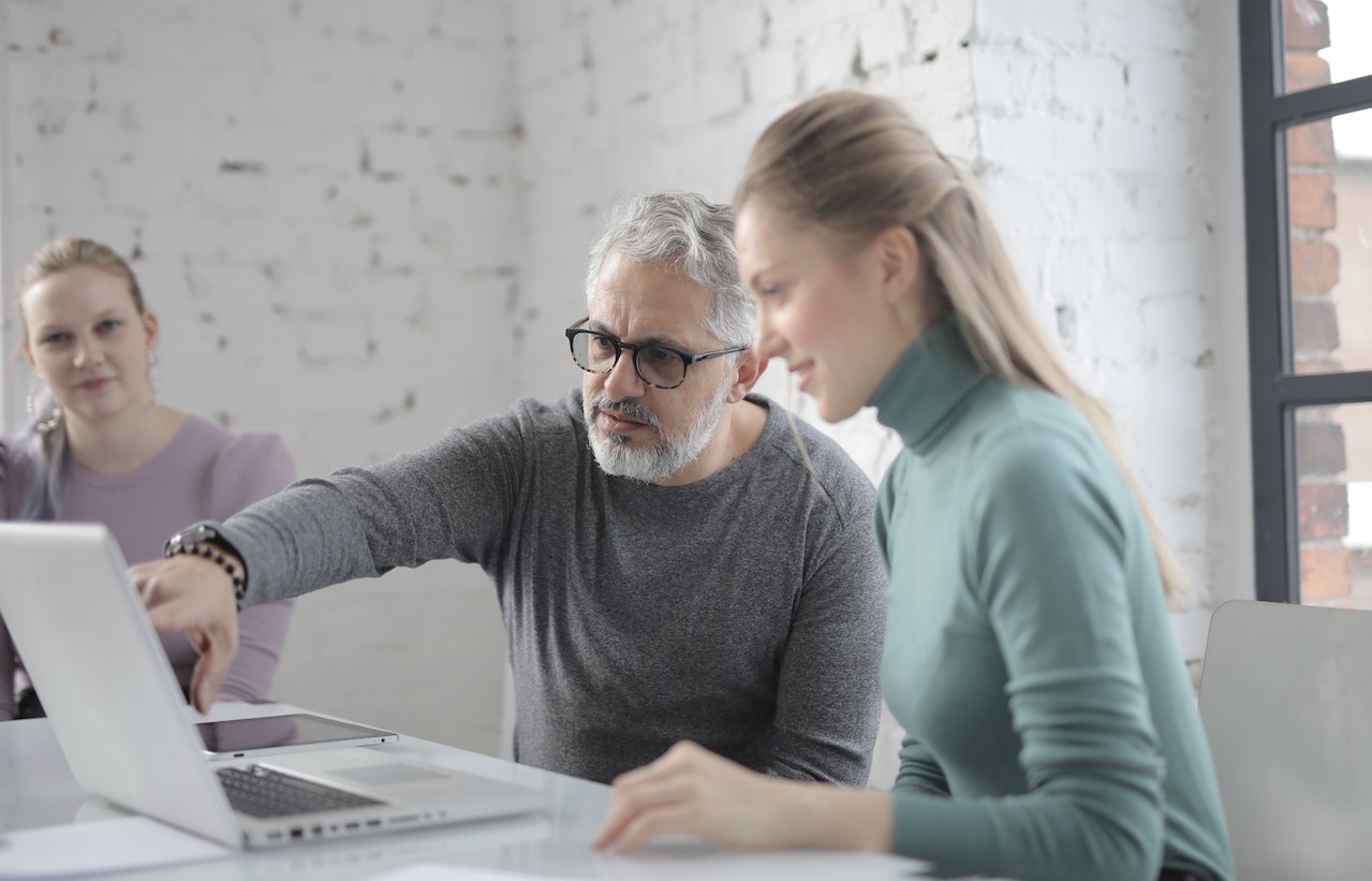 Man training an employee while pointing to a laptop screen